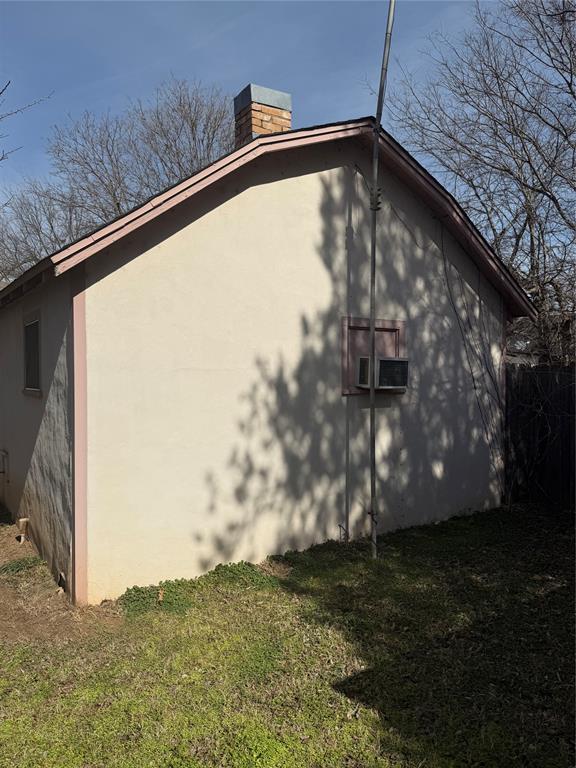 view of side of home featuring a lawn, a chimney, and stucco siding