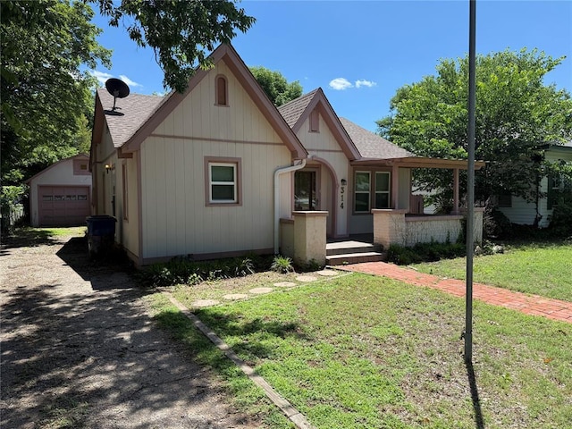 314 W Kentucky Ave, Anadarko, OK 73005 - tudor-style house featuring a shingled roof, a front yard, and an outbuilding