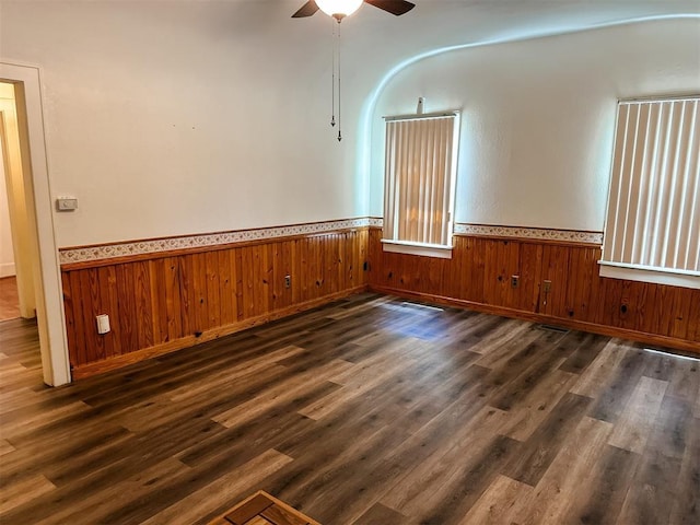 314 W Kentucky Ave, Anadarko, OK 73005 - spare room with a ceiling fan, a wainscoted wall, dark wood-style floors, and wooden walls