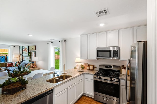 kitchen featuring sink, kitchen peninsula, white cabinets, and appliances with stainless steel finishes