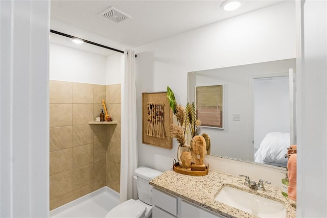 bathroom featuring vanity, toilet, and a tile shower