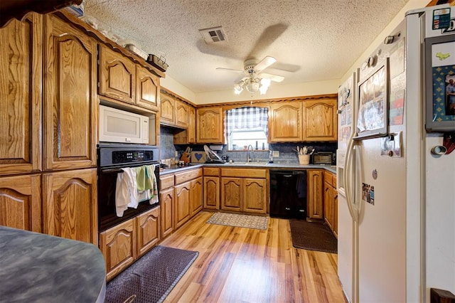 kitchen with sink, decorative backsplash, light hardwood / wood-style floors, black appliances, and a textured ceiling