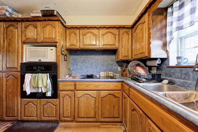 kitchen with sink, a textured ceiling, and black appliances