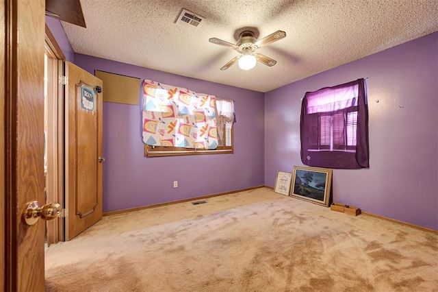 unfurnished room featuring ceiling fan, light carpet, and a textured ceiling