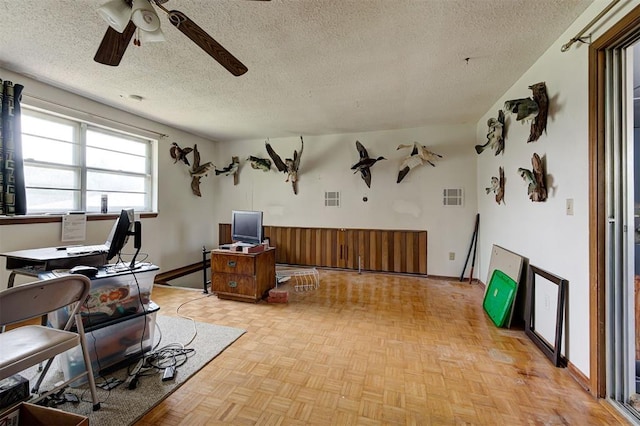 interior space featuring ceiling fan, light parquet flooring, and a textured ceiling