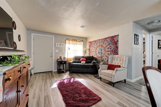 living room featuring light hardwood / wood-style flooring and a textured ceiling