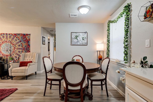 dining space featuring light hardwood / wood-style floors and a textured ceiling