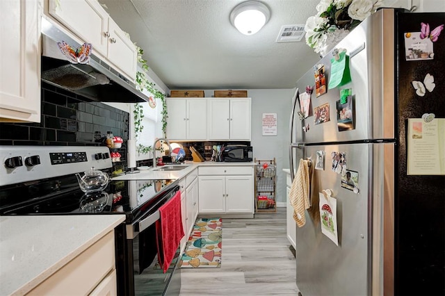 kitchen featuring appliances with stainless steel finishes, tasteful backsplash, white cabinetry, sink, and light hardwood / wood-style floors