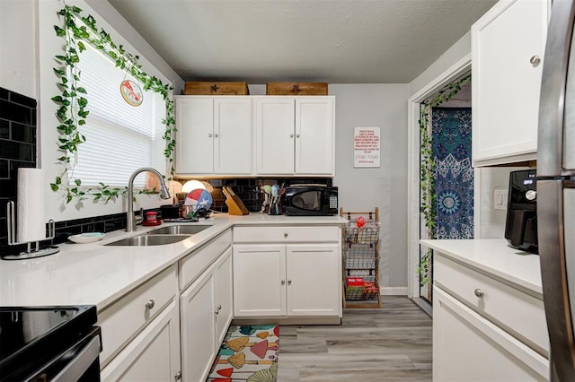 kitchen featuring sink, backsplash, white cabinets, and light hardwood / wood-style floors