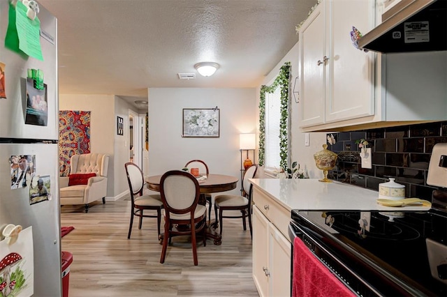 kitchen featuring range with electric cooktop, stainless steel refrigerator, white cabinetry, backsplash, and light hardwood / wood-style floors