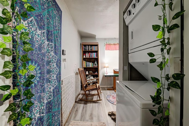 interior space with stacked washer and dryer, ornamental molding, and hardwood / wood-style flooring