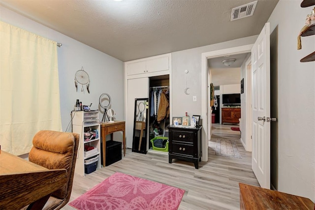 bedroom featuring light hardwood / wood-style flooring, a closet, and a textured ceiling