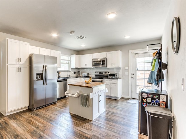 kitchen featuring butcher block countertops, white cabinetry, stainless steel appliances, a center island, and dark hardwood / wood-style flooring