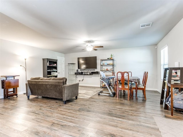 living area with light wood-style floors, visible vents, ceiling fan, and baseboards