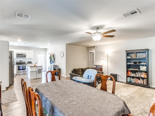 dining area with a ceiling fan, light wood-style floors, visible vents, and baseboards