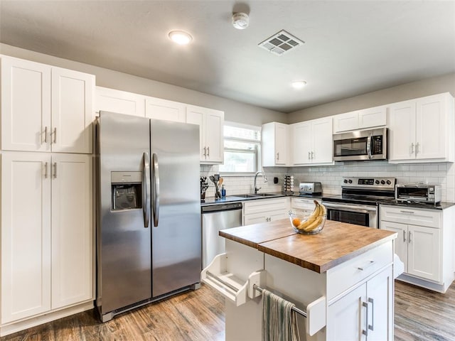 kitchen with appliances with stainless steel finishes, white cabinets, visible vents, and a sink