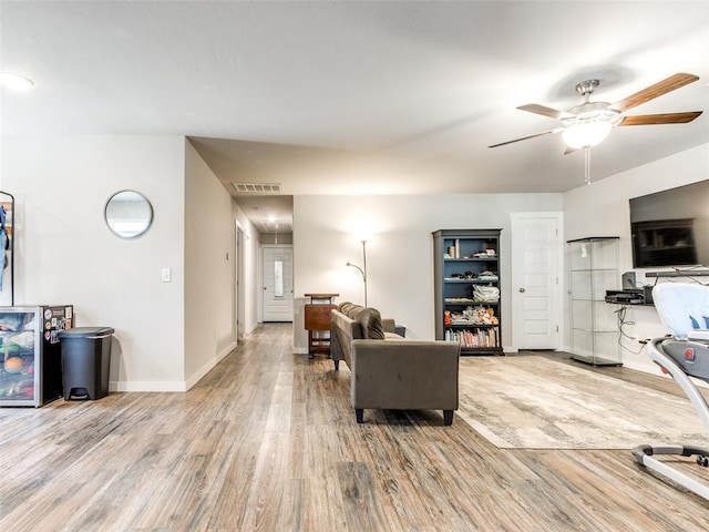 living area featuring visible vents, attic access, ceiling fan, wood finished floors, and baseboards