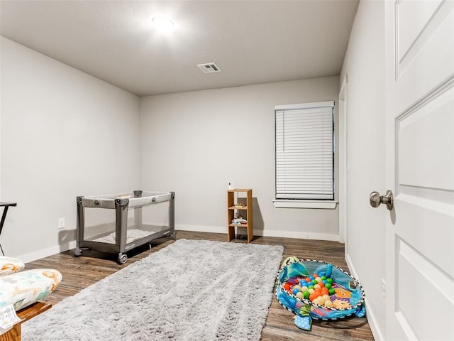 recreation room with dark wood-type flooring, visible vents, and baseboards