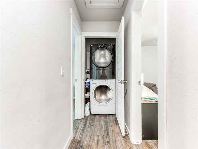 laundry area with wood finished floors, stacked washer and clothes dryer, and laundry area