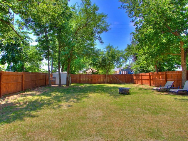 view of yard with a storage shed, an outdoor fire pit, an outdoor structure, and a fenced backyard