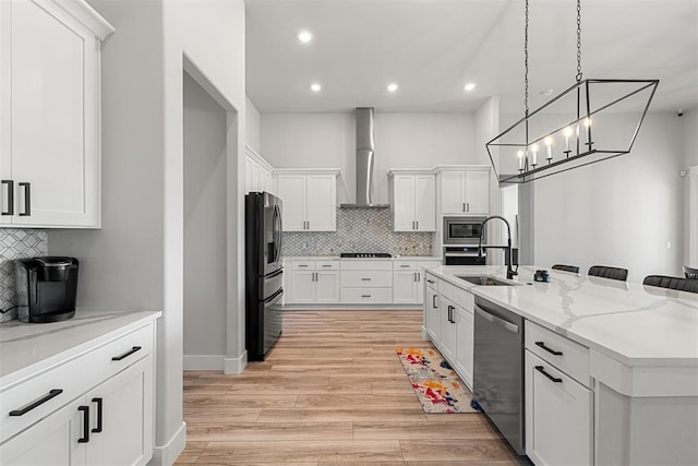 kitchen with wall chimney exhaust hood, stainless steel appliances, sink, and white cabinets