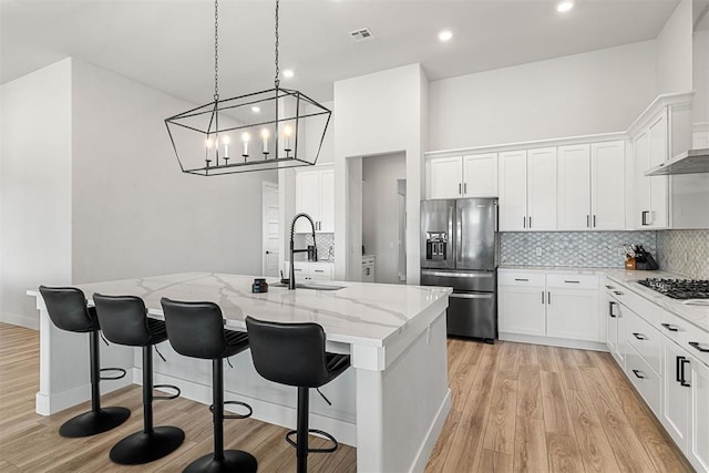 kitchen featuring appliances with stainless steel finishes, a kitchen island with sink, sink, and light stone counters