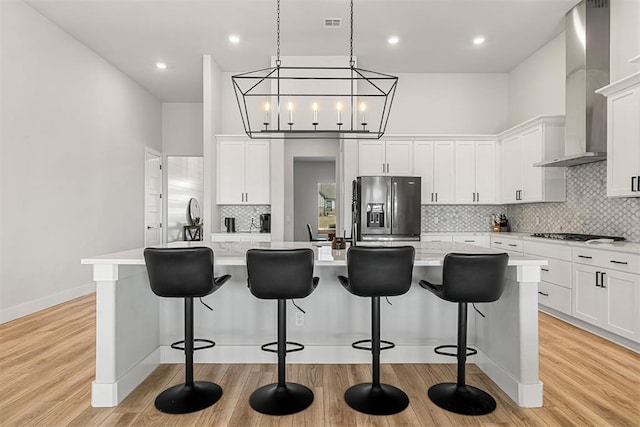 kitchen featuring a spacious island, stainless steel fridge with ice dispenser, and wall chimney range hood