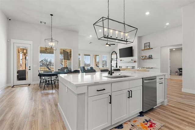 kitchen with light stone countertops, sink, a center island with sink, and white cabinets