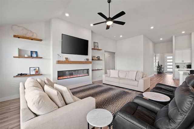 living room with ceiling fan, lofted ceiling, and light wood-type flooring