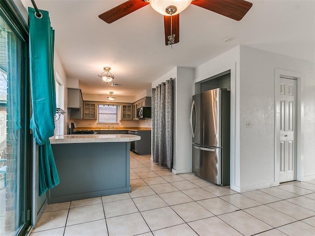 kitchen featuring light tile patterned flooring, appliances with stainless steel finishes, sink, ceiling fan, and kitchen peninsula