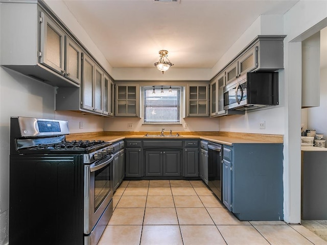 kitchen with light tile patterned floors, gray cabinets, sink, and appliances with stainless steel finishes