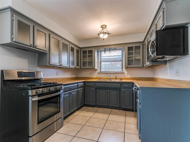 kitchen with light tile patterned floors, sink, appliances with stainless steel finishes, gray cabinetry, and wood counters