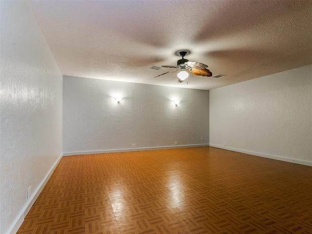 spare room featuring ceiling fan, a textured ceiling, and dark parquet floors