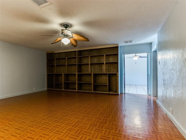 empty room with ceiling fan, parquet flooring, and a textured ceiling