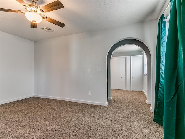 empty room with ceiling fan, a healthy amount of sunlight, and light carpet