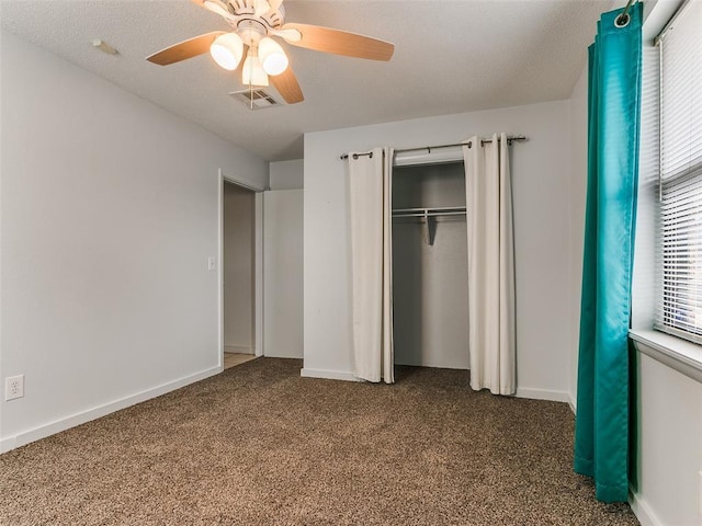 unfurnished bedroom with multiple windows, ceiling fan, carpet flooring, and a closet