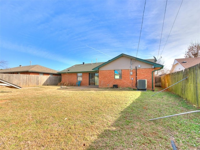 rear view of house with central AC and a yard