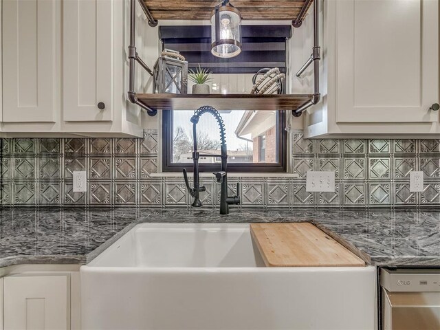 kitchen featuring tasteful backsplash, dark stone counters, sink, and white cabinets