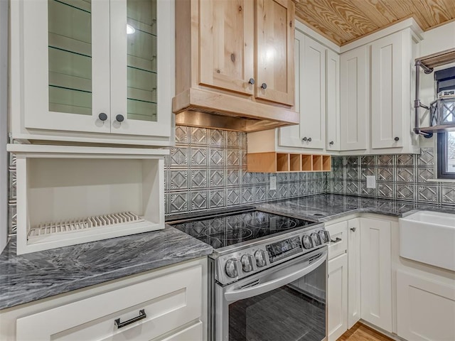 kitchen featuring white cabinetry, dark stone counters, stainless steel electric stove, and tasteful backsplash