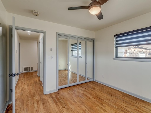 unfurnished bedroom with multiple windows, light hardwood / wood-style floors, a closet, and ceiling fan