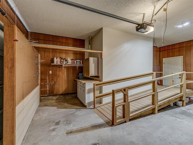 garage featuring a garage door opener and wooden walls