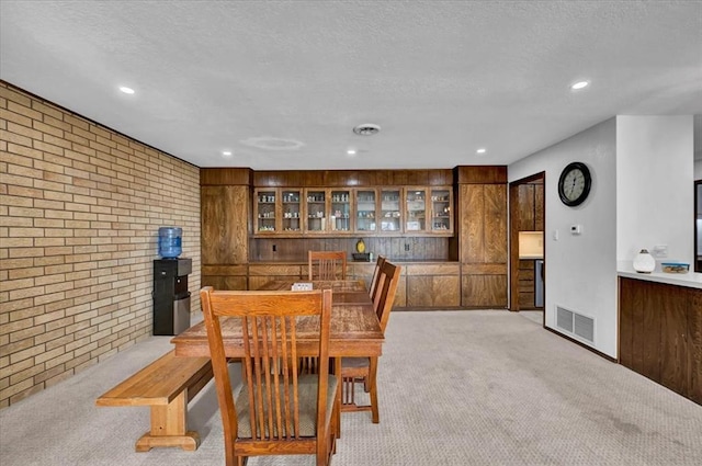 carpeted dining area with brick wall and a textured ceiling