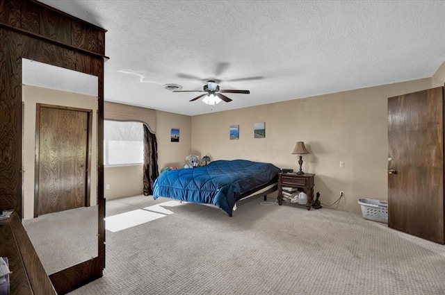 carpeted bedroom with ceiling fan and a textured ceiling