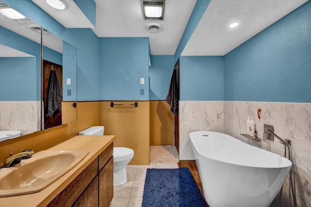 bathroom featuring a tub, tile walls, vanity, toilet, and tile patterned floors