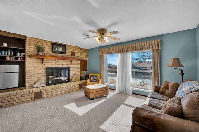 living room featuring light carpet, a brick fireplace, built in shelves, and ceiling fan