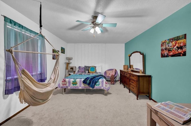 bedroom featuring a textured ceiling, light colored carpet, and ceiling fan