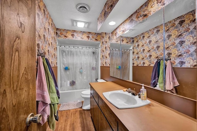 full bathroom featuring hardwood / wood-style flooring, vanity, shower / tub combo, toilet, and a textured ceiling