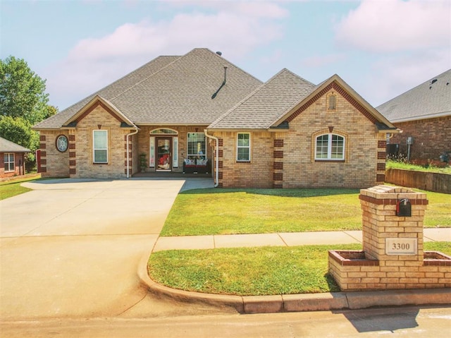 view of front of home featuring brick siding, roof with shingles, and a front yard