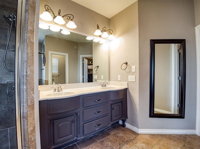 full bathroom with double vanity, tiled shower, a sink, and baseboards