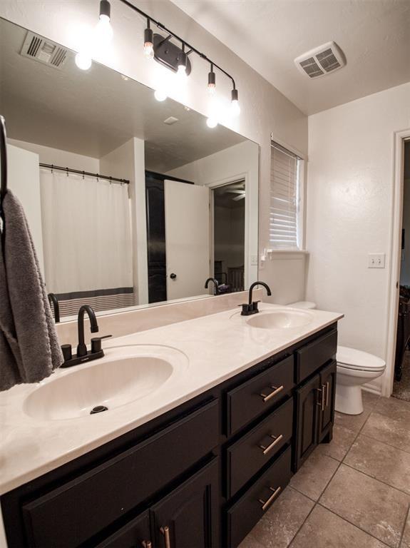 bathroom with toilet, a sink, and visible vents